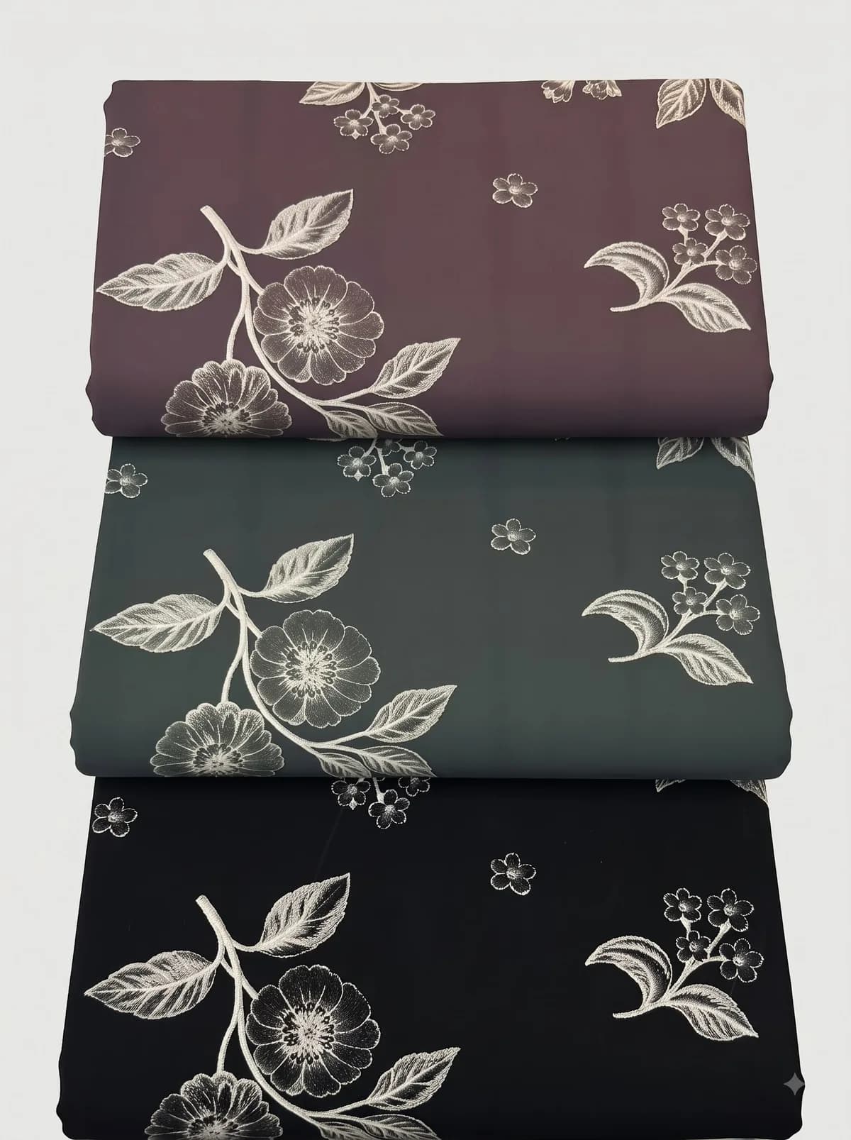 Folded burgundy, forest green and black botanical branch print fabrics