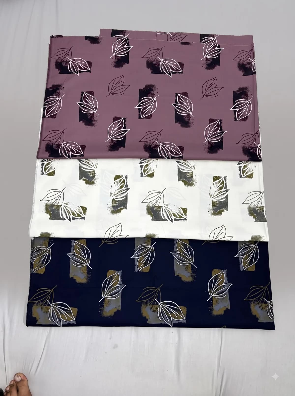 Mauve, ivory and navy leaf outline fabrics with brush-block print laid out for showcase