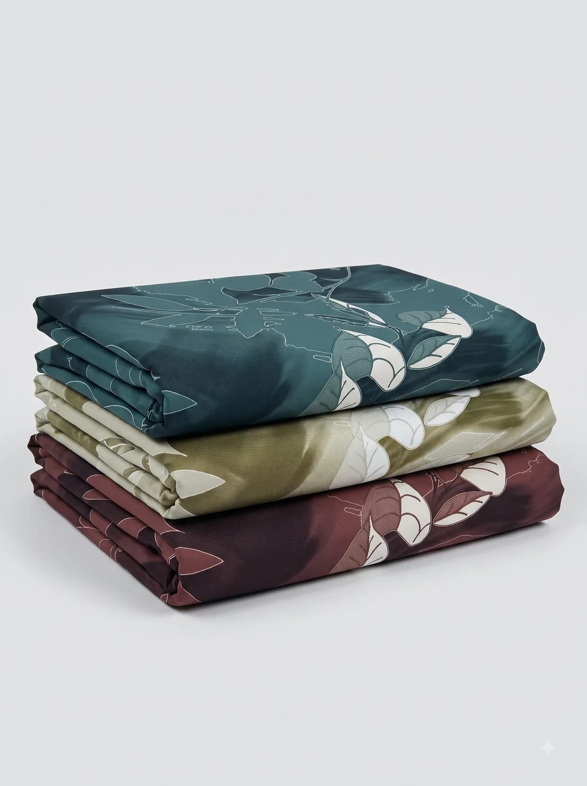 Folded crimson, indigo and charcoal tartan fabrics stacked on a white background