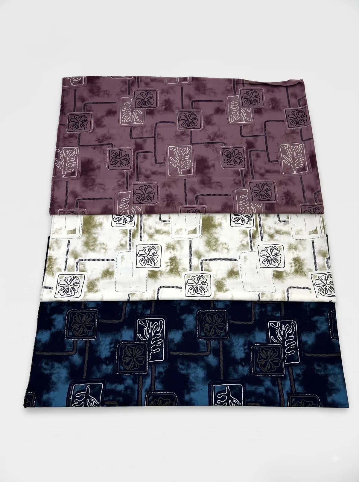 Mauve, ivory and navy lattice floral print fabrics laid out for showcase