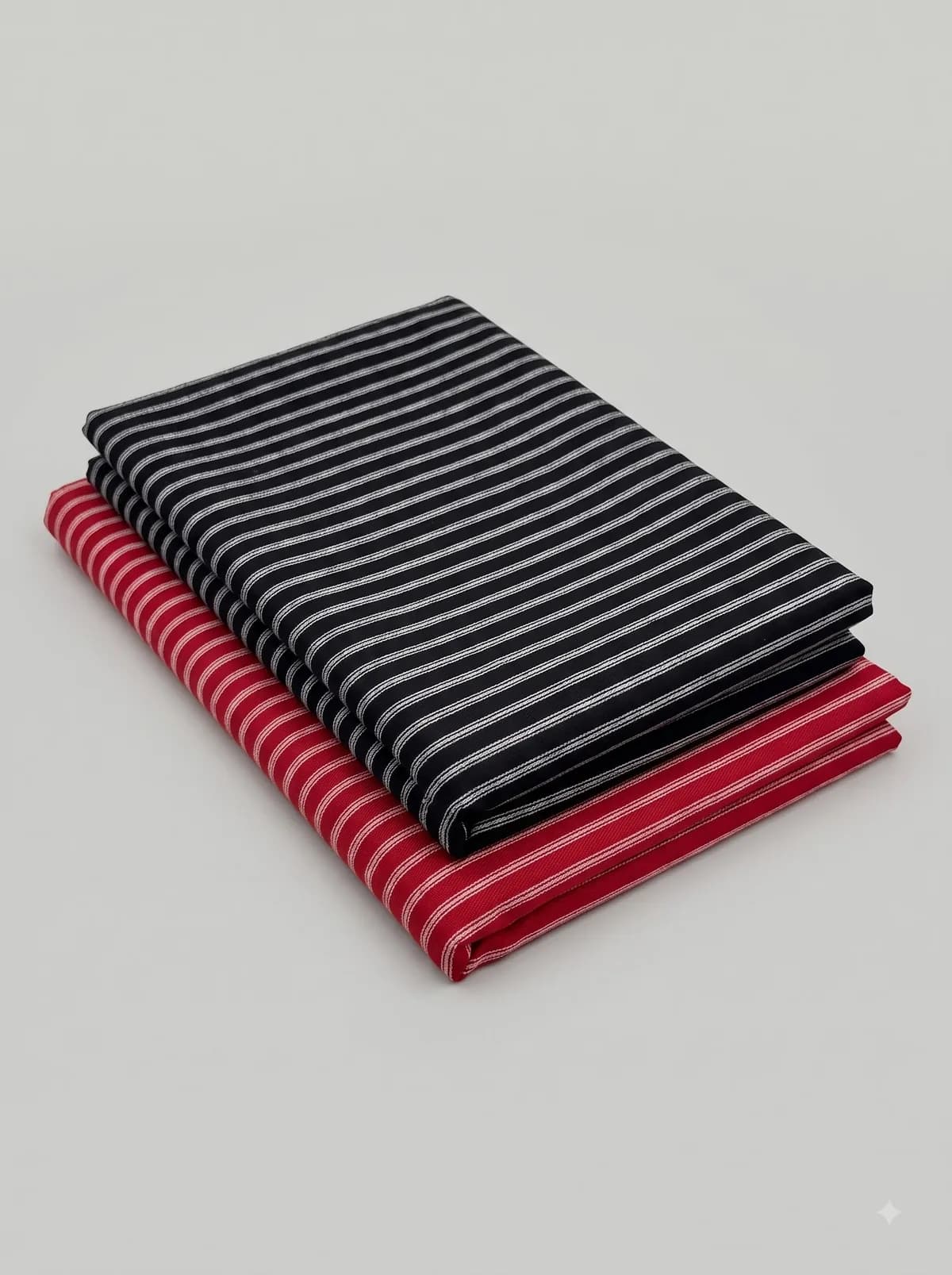 Folded navy and red pencil stripe fabrics stacked on a grey background